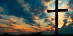 Cruz no fim de tarde com luz brilhando atrás